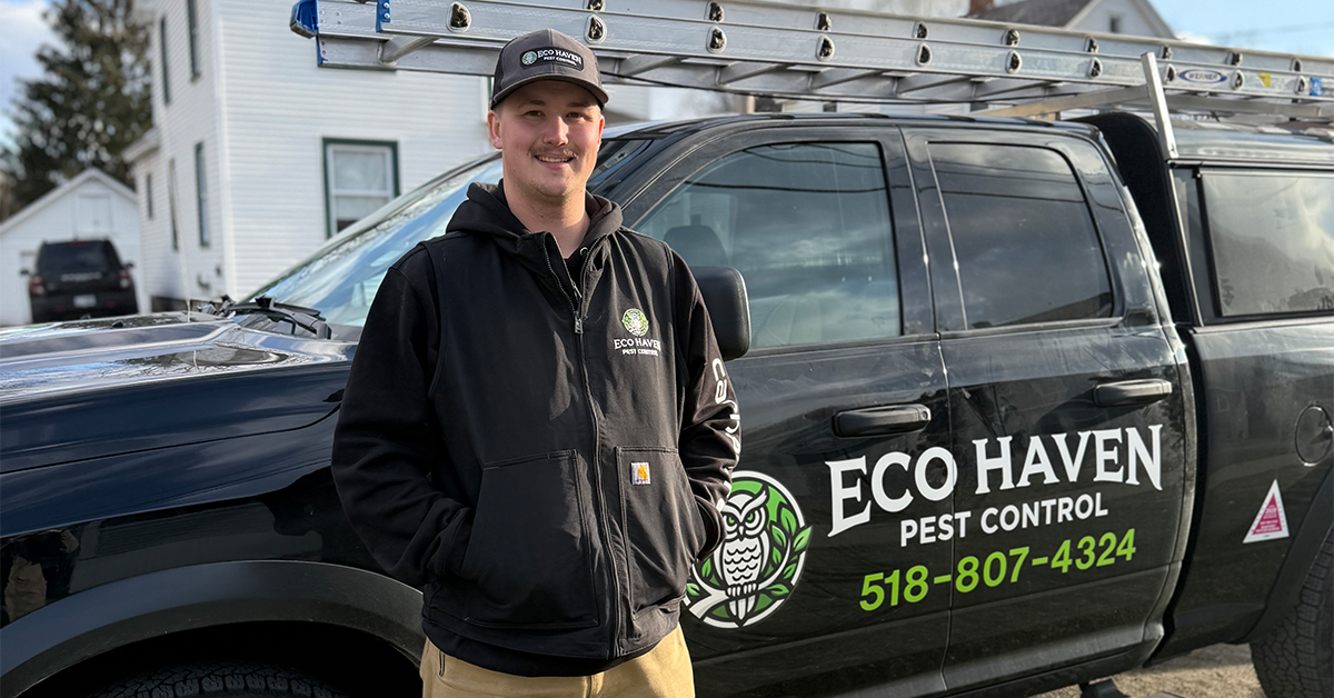 Pest control technician beside branded company truck